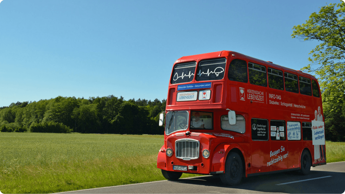 Ein alter, englischer Doppeldeckerbus auf einer Landstraße.